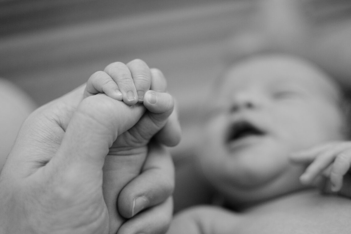 Baby holding the hand of its father