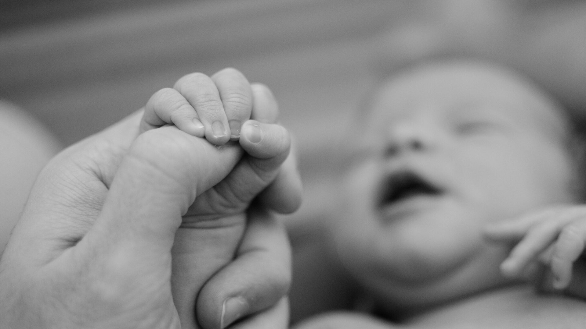 Baby holding the hand of its father